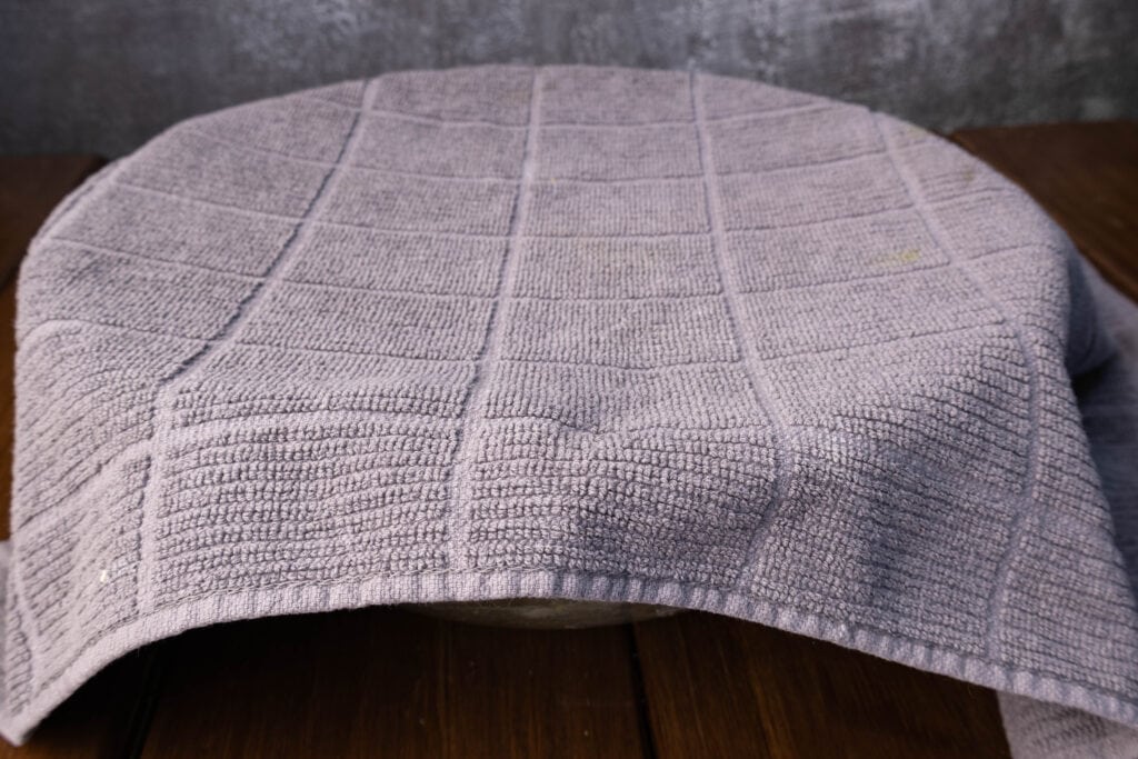 Dough covered with a kitchen towel.