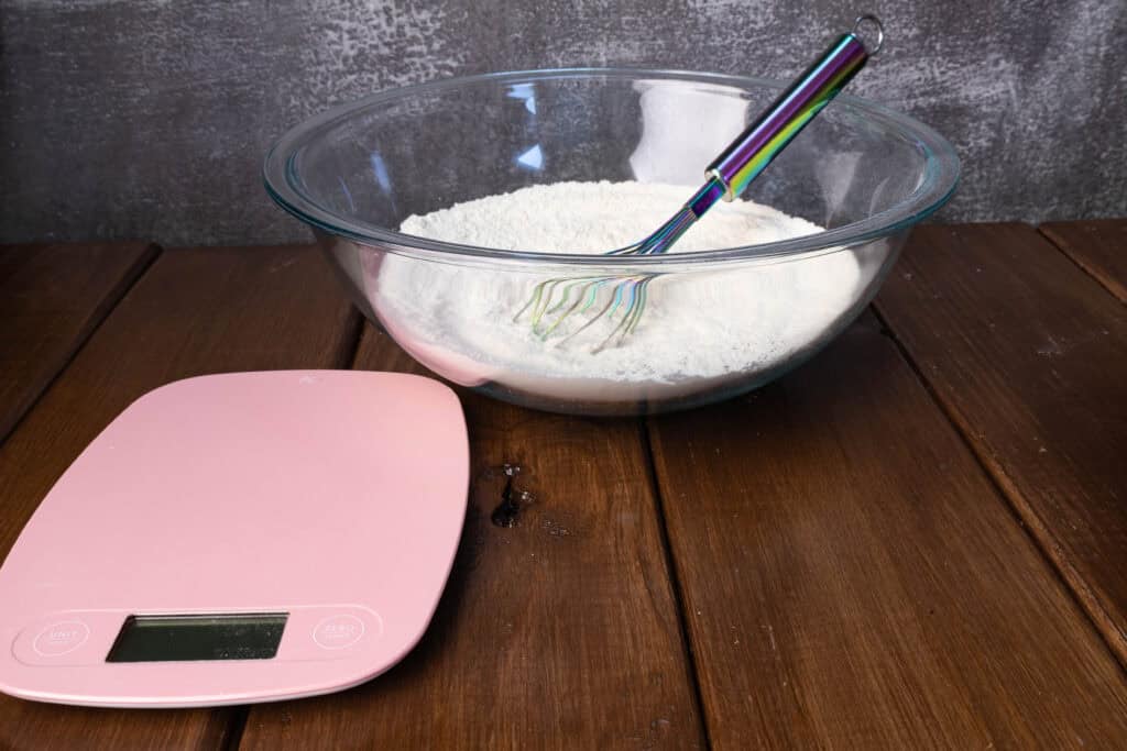 Flour mixture in a glass bowl and a kitchen scale.