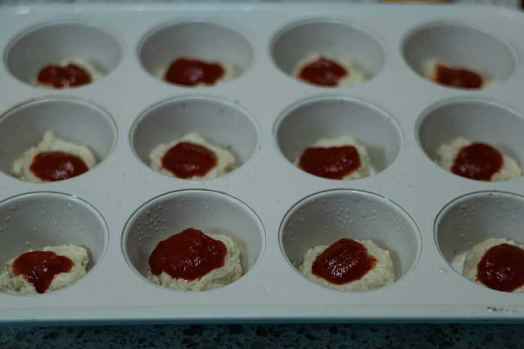 Pizza dough topped with pizza sauce.