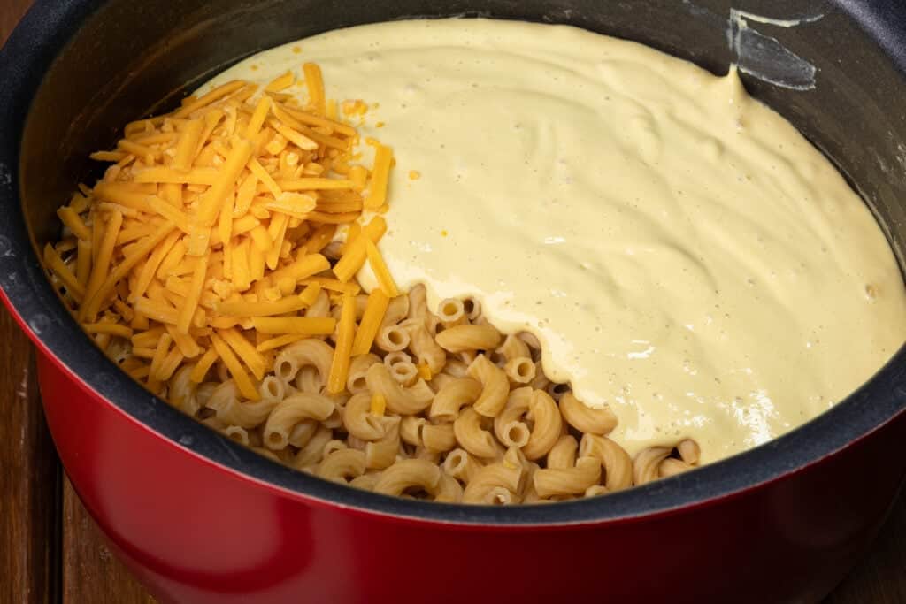 Pot of elbow macaroni, mac and cheese sauce and vegan shredded cheese.