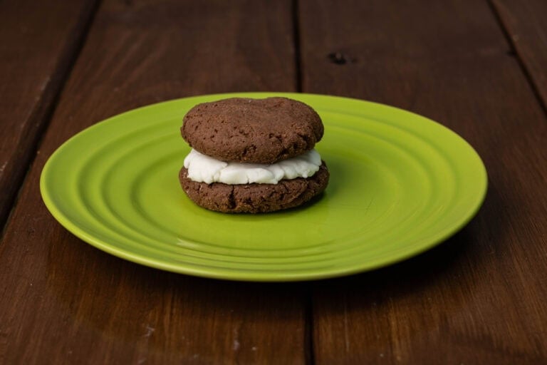 Gluten-free chocolate protein sandwich cookie on a green plate.