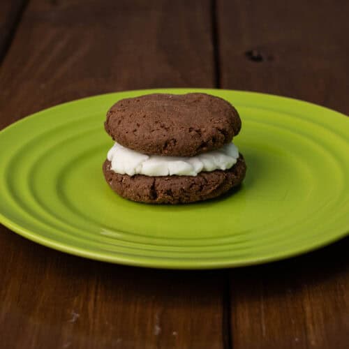 Gluten-free chocolate protein sandwich cookie on a green plate.