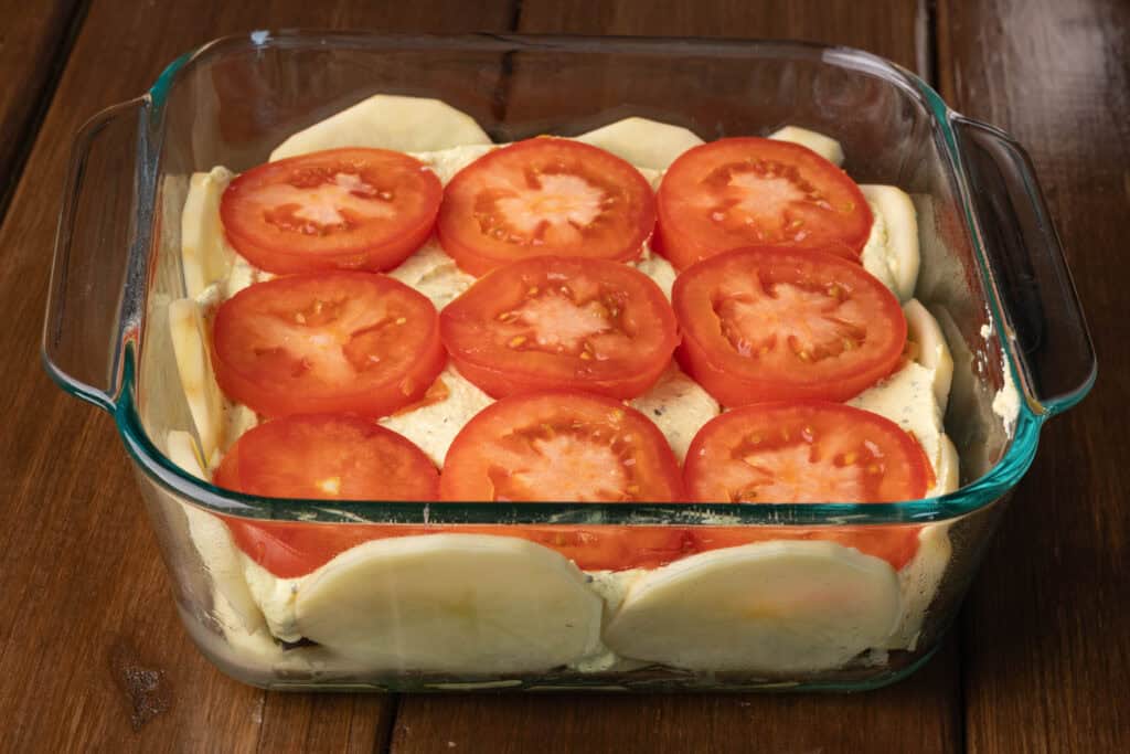 Potato quiche, unbaked, topped with sliced tomatoes.