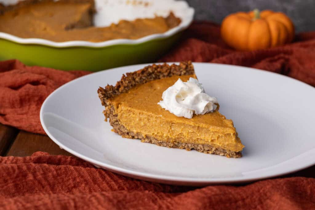 Vegan pumpkin pie on a plate on a Fall themed table.
