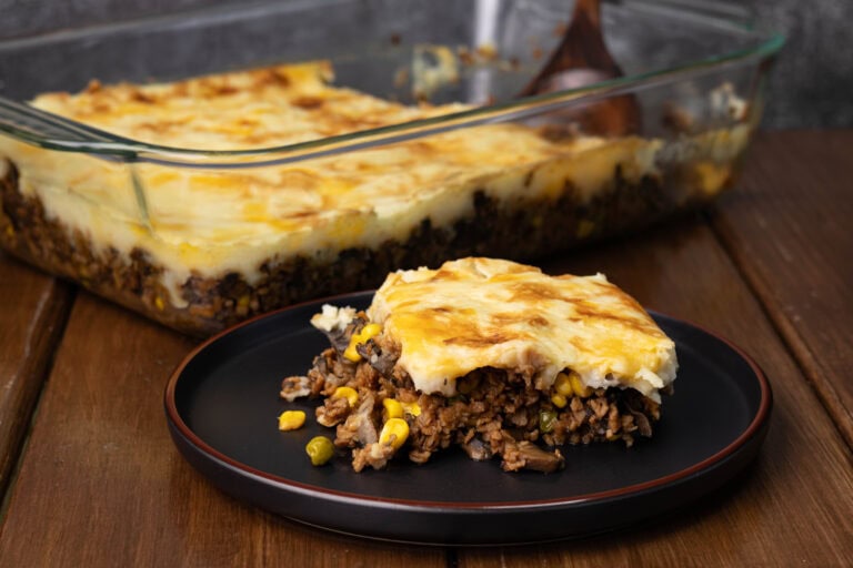 Vegan Shepherd's Pie on a plate with a casserole dish full of the remaining in the background.