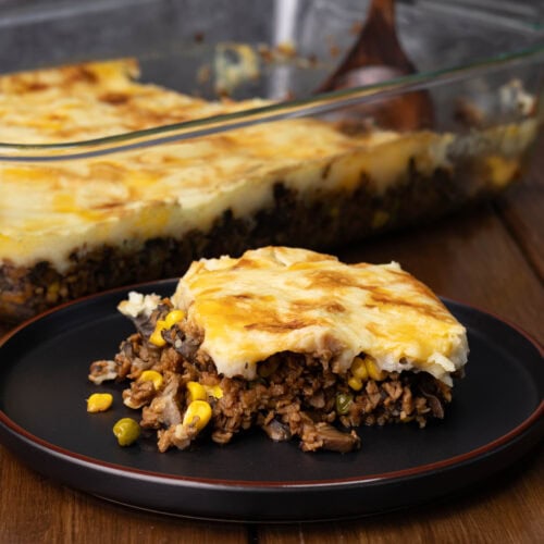 Vegan Shepherd's Pie on a plate with a casserole dish full of the remaining in the background.