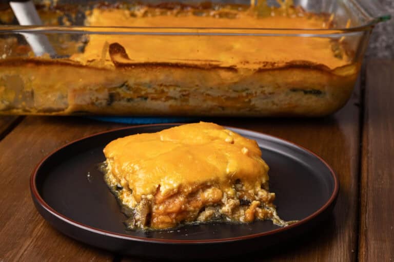 Plate of sweet potato gratin with a big dish with the remaining gratin in the background.