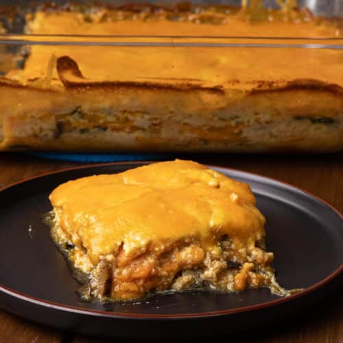 Plate of sweet potato gratin with a big dish with the remaining gratin in the background.