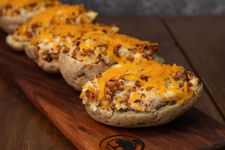 A bunch of twice baked potatoes topped with vegan bacon. bits and melted shredded cheese.