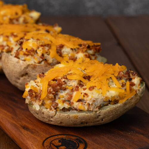 A bunch of twice baked potatoes topped with vegan bacon. bits and melted shredded cheese.