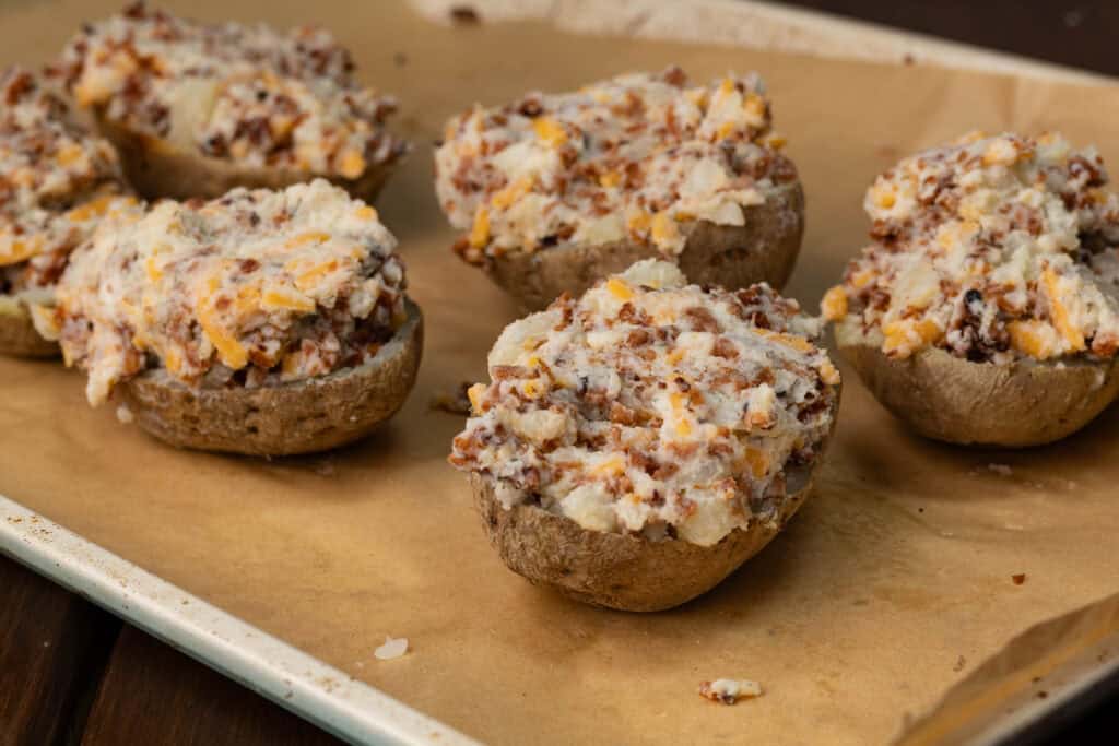 Twice baked potatoes on a parchment paper lined baking sheet.