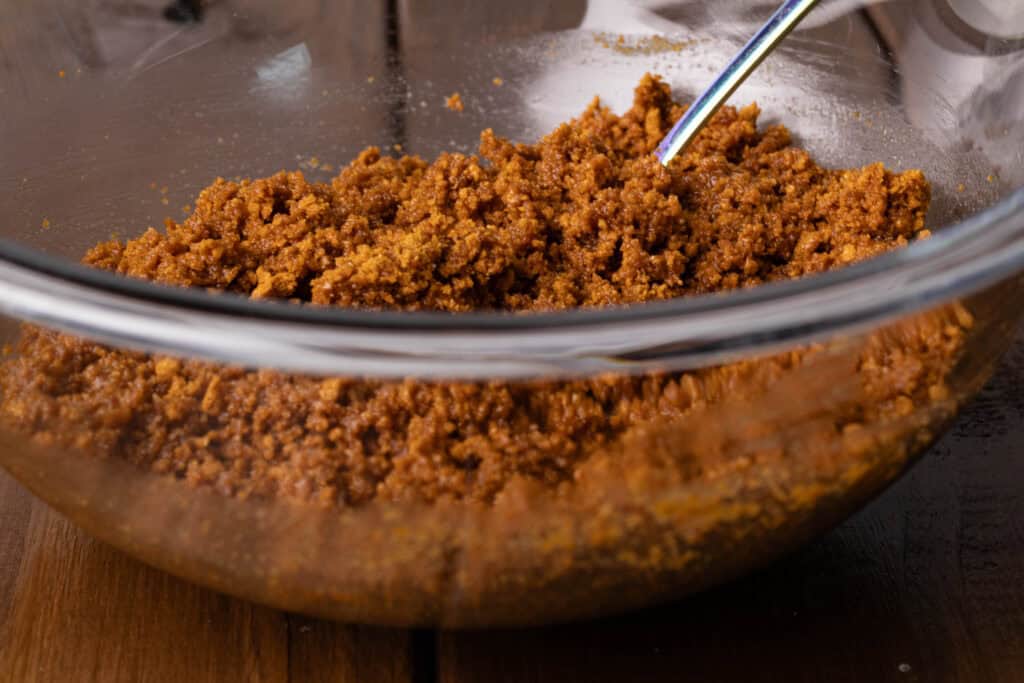 Crushed Biscoff cookies and melted butter mixed together in a bowl.
