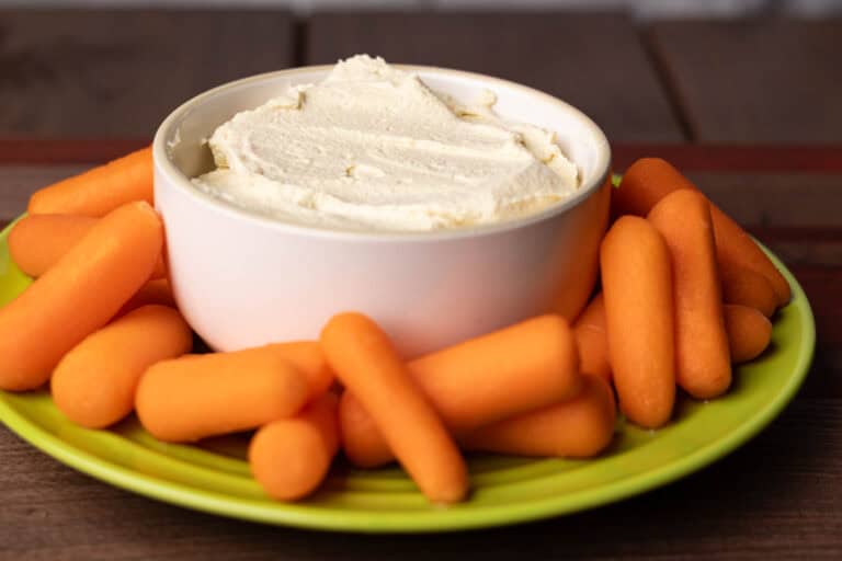 Tofu hummus on a plate with baby carrots.