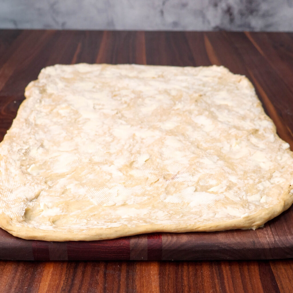 Cinnamon roll dough rolled out with butter.