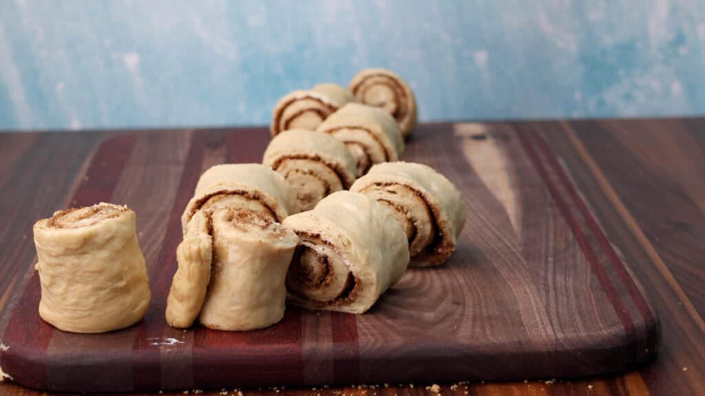 Uncooked vegan cinnamon rolls on a cutting board.
