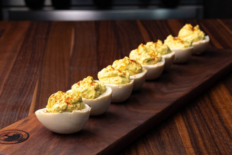 Vegan deviled eggs on a wooden cutting board.