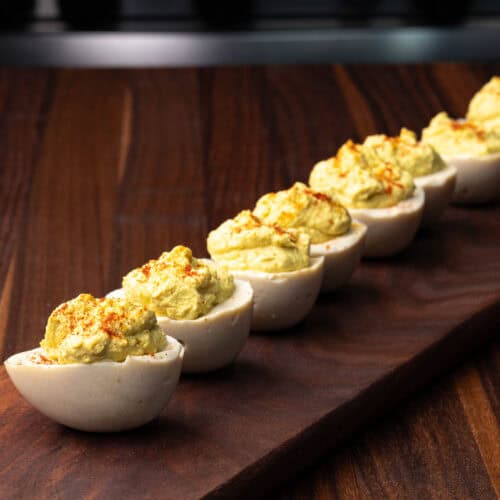 Vegan deviled eggs on a wooden cutting board.