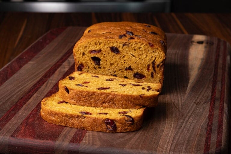High protein orange cranberry loaf on a wooden cutting board.