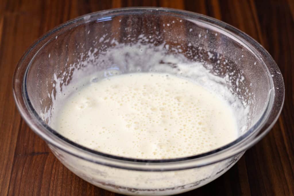 Creamy vegan protein shake in a glass bowl on wooden surface.