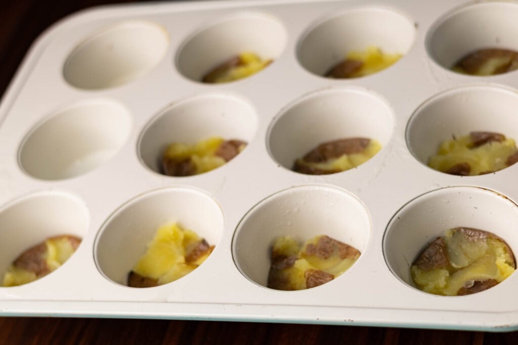 Smashed baby potatoes in a muffin tin.