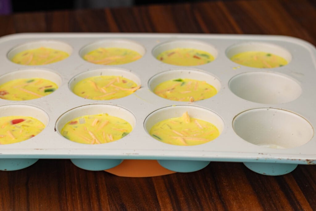 Vegan egg bites, uncooked, in a muffin tin.