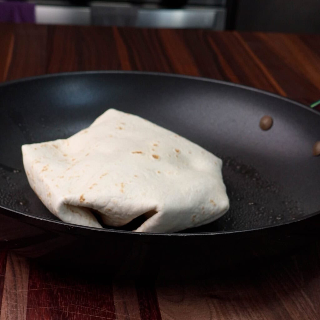 Crunchwrap cooking in a pan.