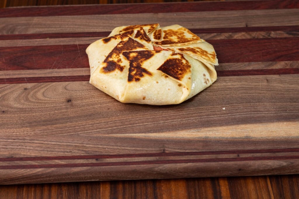 A TVP Crunchwrap Supreme on a wooden cutting board.
