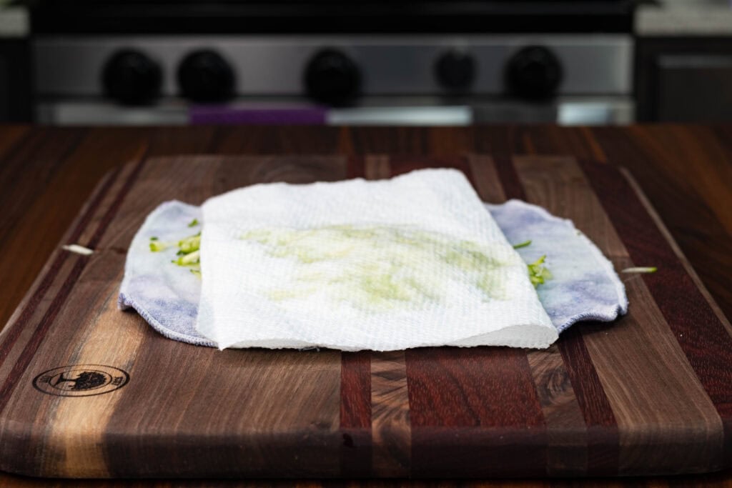Shredded zucchini being dried with a paper towel.