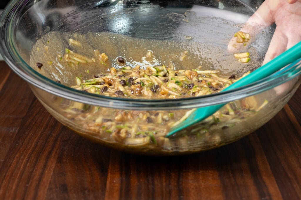 Wet ingredients plus zucchini, chocolate chips and nuts mixed together in a bowl.